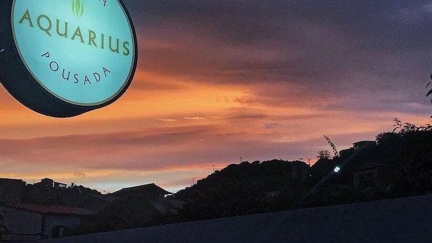 Señal de 'Osteria Aquarius Pousada' contra un cielo al atardecer.