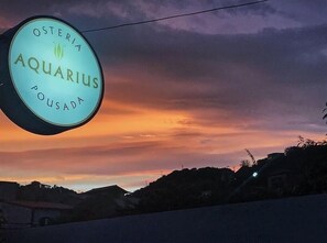 A sign for 'Osteria Aquarius Pousada' against a sunset sky. - Aquarius Osteria (Arraial do Cabo)