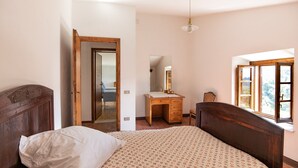 A bedroom with a bed, a wooden desk, a mirror, and a window with a view. - Casa Gabriello (Pescaglia)