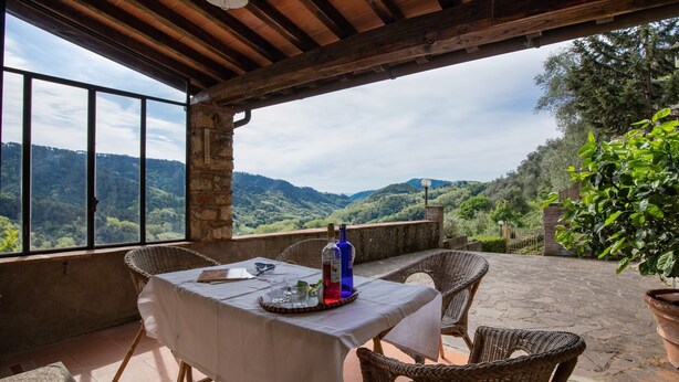 A terrace with a table set for two, overlooking a mountainous landscape. - Casa Gabriello (Pescaglia)