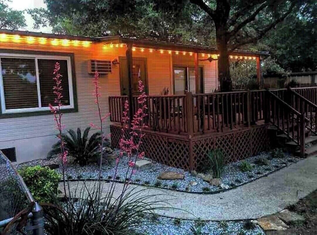 A house with a wooden deck, a covered porch, and a string of lights.