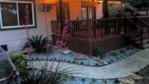 Une maison avec une terrasse en bois, un porche couvert et une guirlande de lumières.