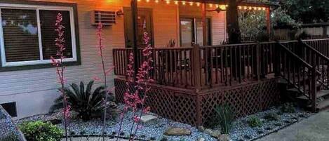 A house with a wooden deck, a covered porch, and a string of lights.