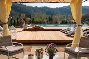 A wooden deck with lounge chairs and a pool, overlooking a mountainous landscape. - Casale Isidora (Camaiore)