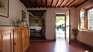 A wooden interior with a stone wall, a wooden bench, and a door leading outside. - Casa Paola (Camaiore)