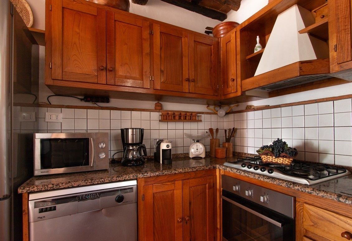A kitchen with wooden cabinets, a microwave, a coffee maker, a scale, and a gas stove.