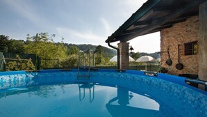 A swimming pool with a tiled edge, a ladder, and a pergola structure. - Casa Paola (Camaiore)