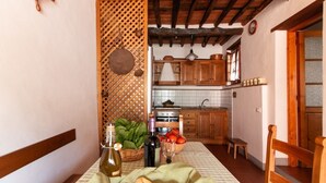 A cozy kitchen with wooden cabinets, a tiled backsplash, and a checkered tablecloth. - Casa Paola (Camaiore)