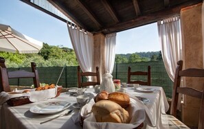 An outdoor dining area with a table set for breakfast, including bread, pastries, and tea. - Casa Paola (Camaiore)
