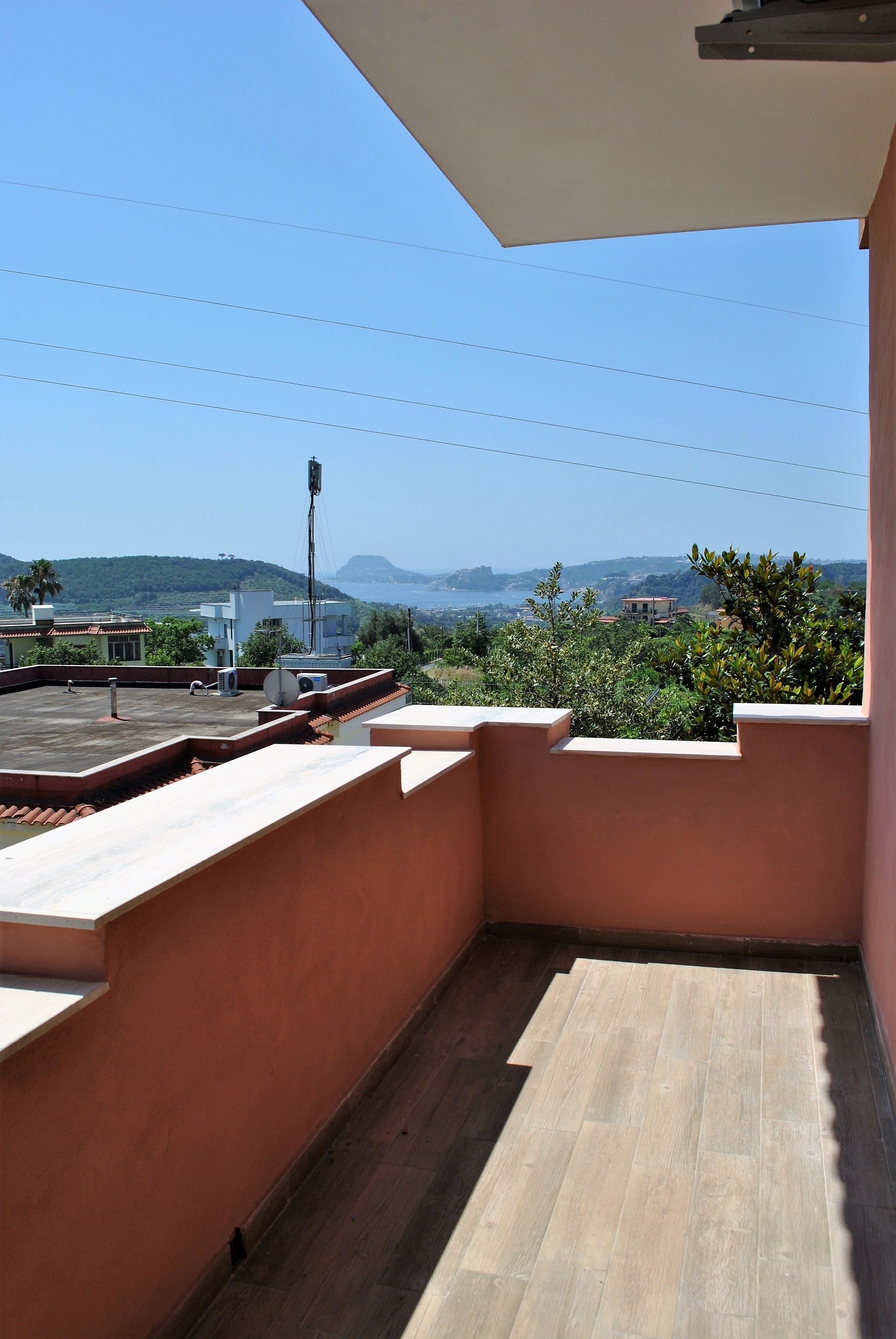 A rooftop terrace with a view of the sea and hills.