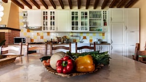 A kitchen with white cabinets, a microwave, and a fruit basket on the counter. - Il Castagno (Camaiore)