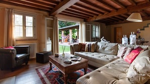 A spacious living room with a wooden ceiling, a sofa set, a coffee table, and a view of the outdoors. - Il Castagno (Camaiore)