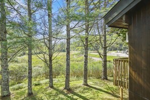 A wooden cabin with a deck overlooking a forested area. - Two Queen bed Standard Hotel room 204 (Killington)