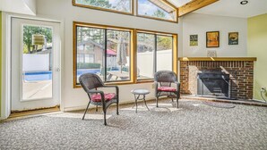 Une pièce dotée de grandes fenêtres, d’une cheminée et de fauteuils en osier.