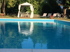 A swimming pool with a gazebo and lounge chairs. - Villa Cesarina (Vallio Terme)