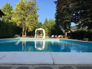 A swimming pool with a gazebo, lounge chairs, and surrounding trees. - Villa Cesarina (Vallio Terme)