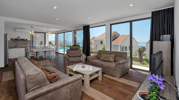 A spacious living room with a large window, a dining area, and a kitchen. - Modern house with private pool, family-friendly, WiFi, barbecue, sea view, quiet (Makarska)