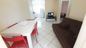 Un espace de vie compact comprenant un coin repas, un canapé et un téléviseur.