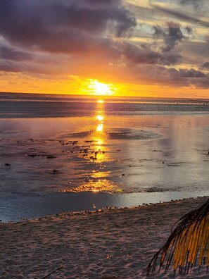 A beach with a sunset over the ocean, clear skies, and calm waters reflecting the sun. - Raukura holiday homes 2 w/free unlimited wifi, a/c, easy beach access.  (Kauare Tapere)