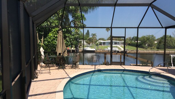 Una piscina techada con vistas a un lago y una casa al fondo.