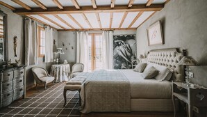 Un dormitorio con una cama grande, una silla, un tocador y una ventana.