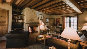 Una sala de estar acogedora con chimenea, estanterías, televisor y asientos cómodos.
