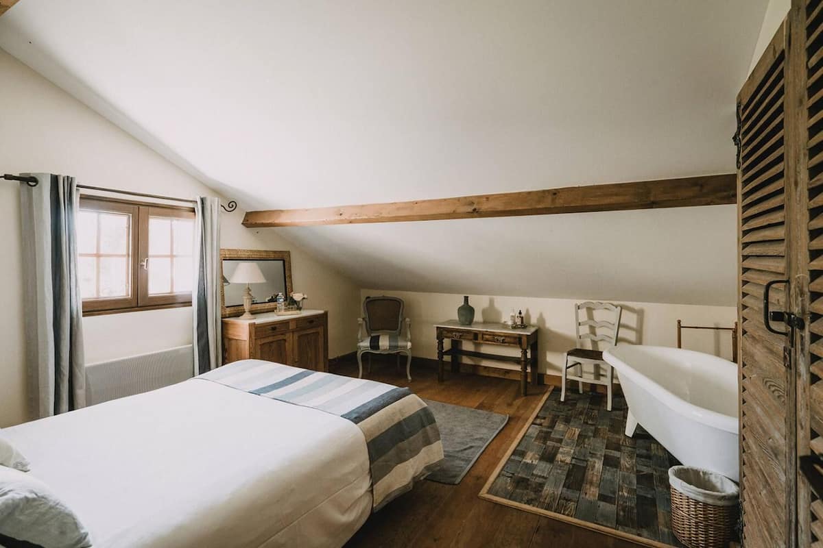 A cozy bedroom with a bed, a desk, a chair, and a small table.