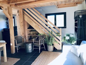 A cozy living room with a wooden staircase, wicker furniture, and a white sofa. - Le Domaine de Petiosse (Saint-Julien-en-Born)