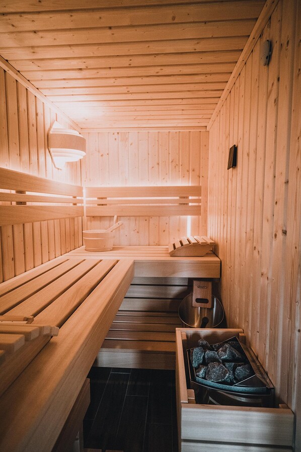 Una sauna con bancos de madera y una pileta de piedra.