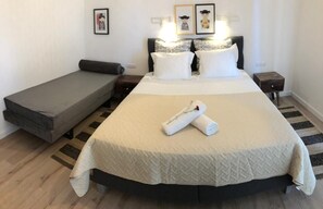 Une chambre à coucher bien rangée, avec un grand lit, un petit canapé et une table de chevet.