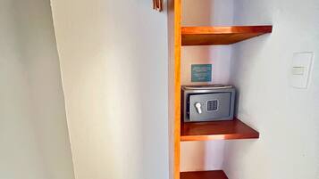 Habitación de esquina con un estante de madera, una pizarra y una caja fuerte pequeña.