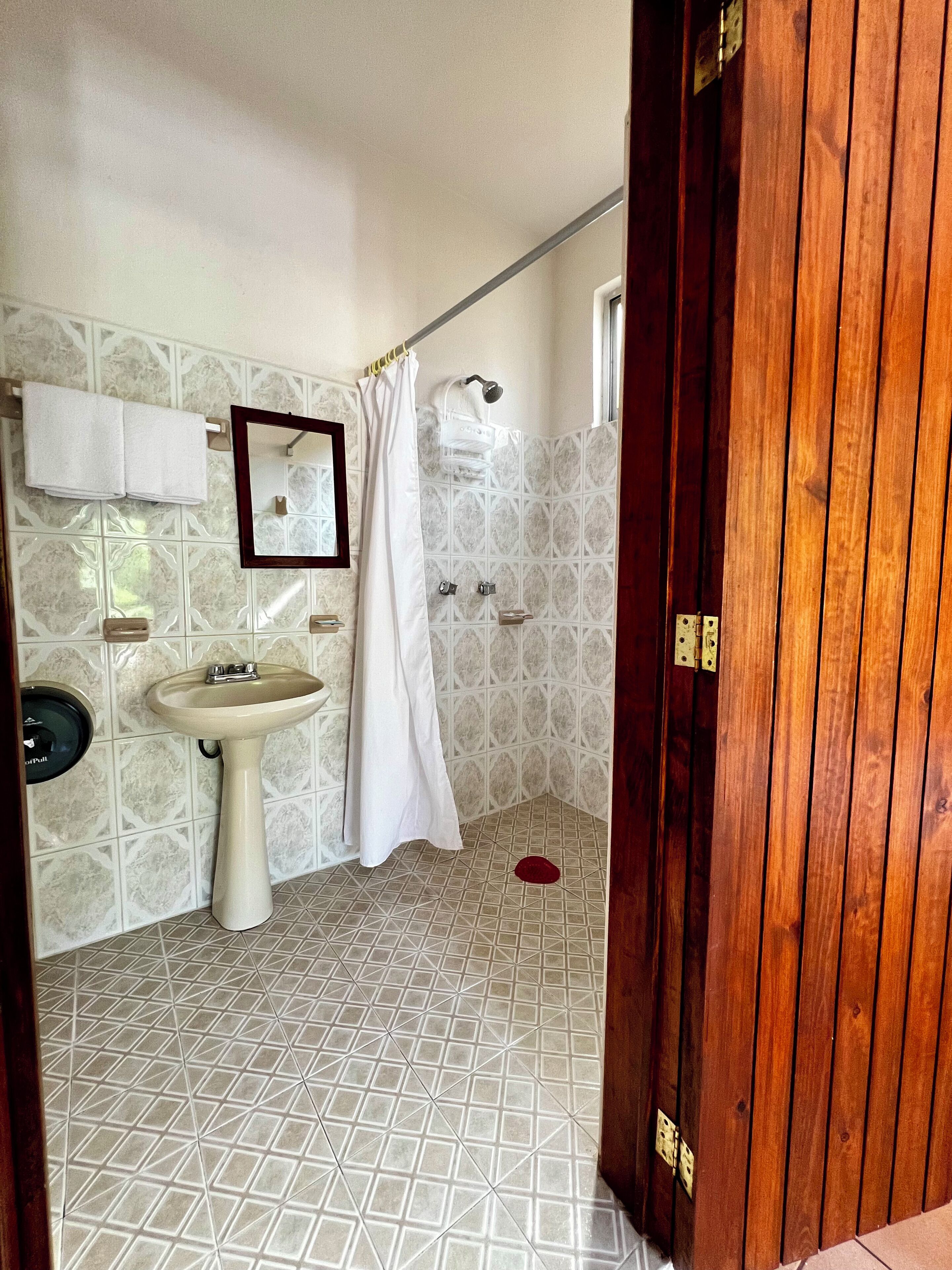 Un baño con lavamanos, espejo y cortina de ducha.