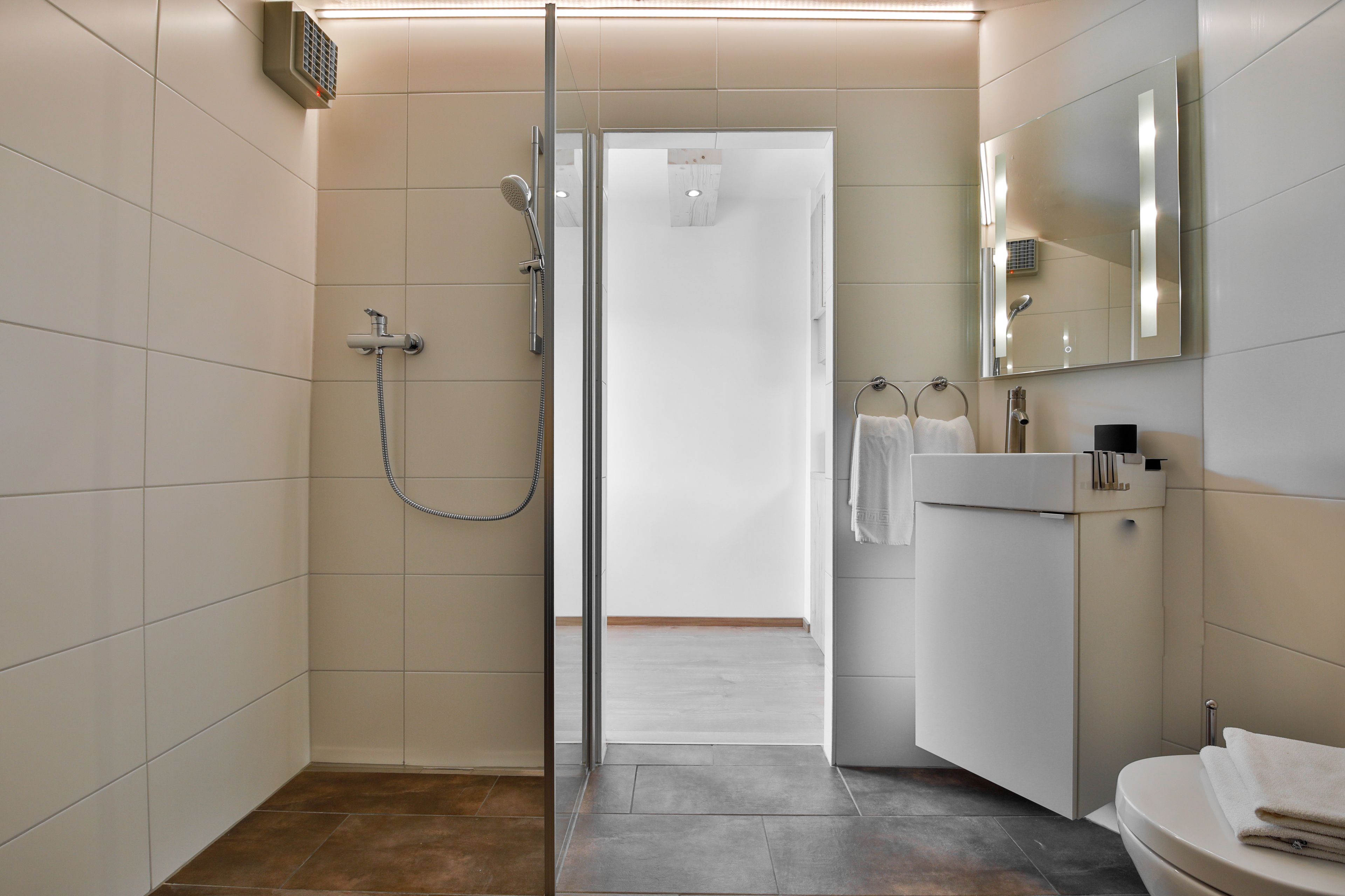 A modern bathroom with a glass shower enclosure, a white sink, and a mirror.