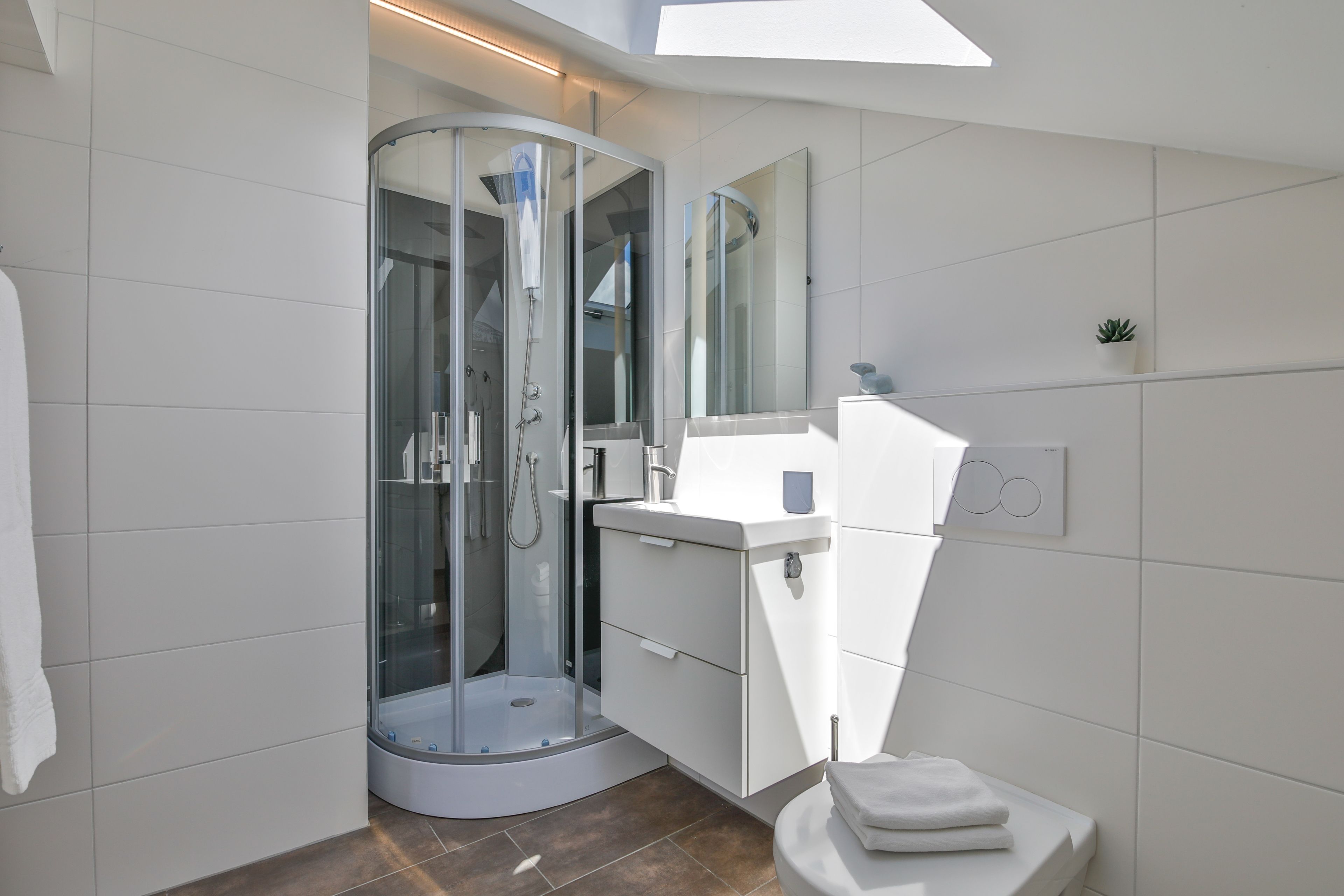 Ein modernes Badezimmer mit einer Duschkabine, einem weißen Waschbecken und einer Toilette.