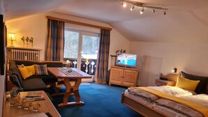 A cozy room with a sofa, a dining table, a bed, and a television. - Wetterstein with mountain panorama view (Untergrainau)