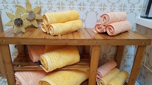 A wooden table with neatly rolled towels in yellow and pink colors, and a decorative flower on the table. - Wetterstein with mountain panorama view (Untergrainau)
