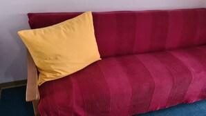 A red sofa with a yellow pillow against a plain wall. - Wetterstein with mountain panorama view (Untergrainau)
