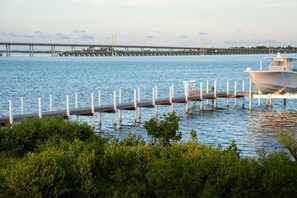 A marina with a dock extending into calm waters, a bridge in the background, and lush greenery in the foreground. - Keys Beach houses with a daily, rental license. Just remodeled (Summerland Key)