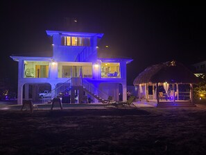 A two-story building with a balcony and a thatched-roof structure.