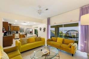 A modern living room with yellow sofas, a glass coffee table, and a view of a bridge. - Keys Beach houses with a daily, rental license. Just remodeled (Summerland Key)