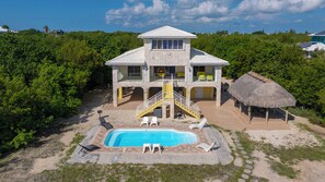 A two-story house with a swimming pool, outdoor seating, and a thatched-roof structure. - Keys Beach houses with a daily, rental license. Just remodeled (Summerland Key)