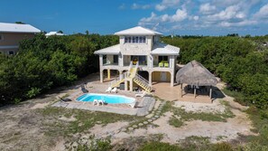 A two-story house with a swimming pool, outdoor seating, and a thatched-roof structure. - Keys Beach houses with a daily, rental license. Just remodeled (Summerland Key)
