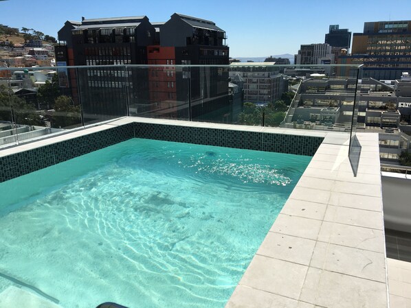 Una piscina en la azotea con agua cristalina, rodeada de edificios de la ciudad y vistas del paisaje urbano.