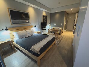Una habitación de hotel moderna con una cama grande, mesitas de noche, un escritorio y una silla.