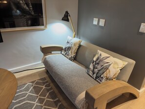 Un salon moderne avec un canapé, une lampe, un tapis et une table basse en bois.