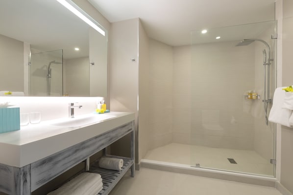 A modern bathroom with a large mirror, a vanity with a sink, and a glass shower enclosure.