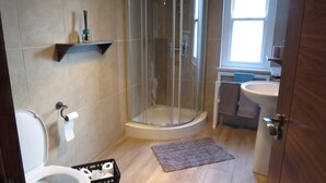 Un baño con inodoro, ducha, lavamanos y ventana.