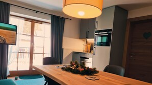 Cozinha moderna com forno Siemens, mesa de jantar de madeira com decoração de Natal, e vista para o exterior por uma janela grande.