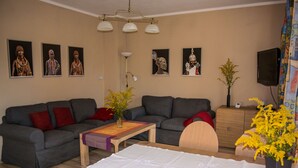Una sala de estar con un sofá gris, una mesa de centro de madera y un televisor sobre un mueble de madera.