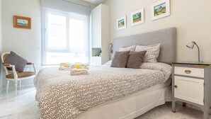 A bedroom with a bed, a chair, a nightstand, and a window. - Quiet and elegance in the Andalusian capital 4 px-WIFI (Sevilla)
